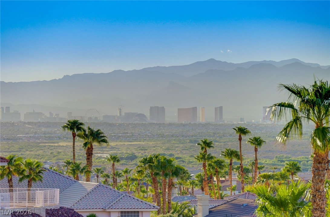 Panoramic view of the Las Vegas skyline and mountains beyond palm-lined homes.