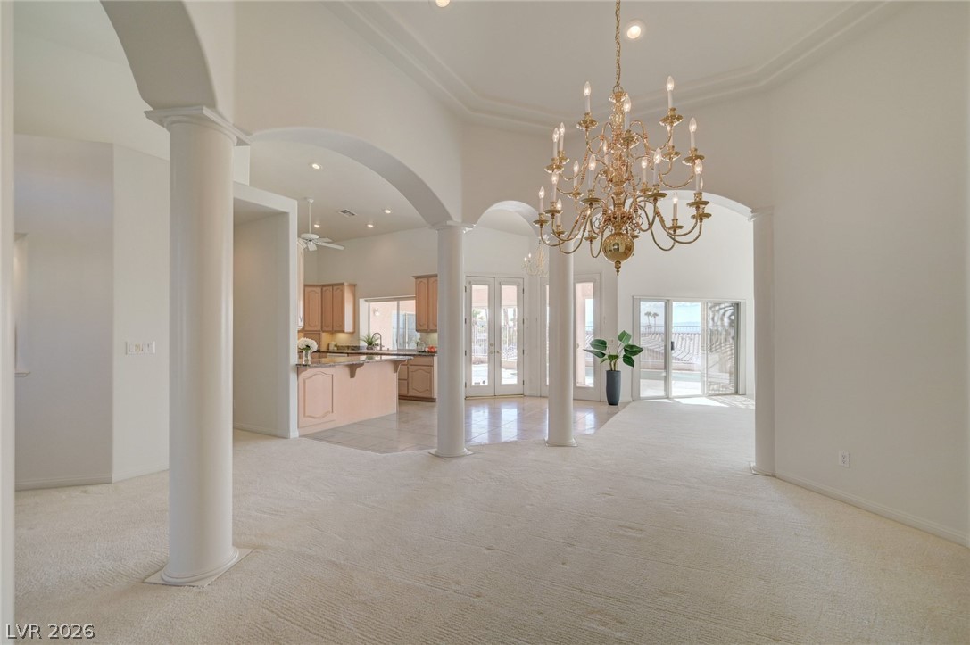 Open-plan living and dining area with an ornate chandelier, arched openings, and adjoining kitchen.