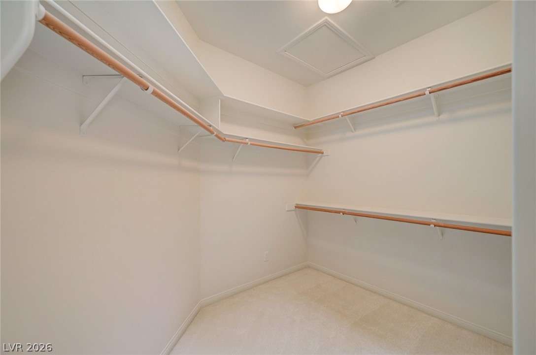 Walk-in closet with built-in shelves and hanging rods on three sides.