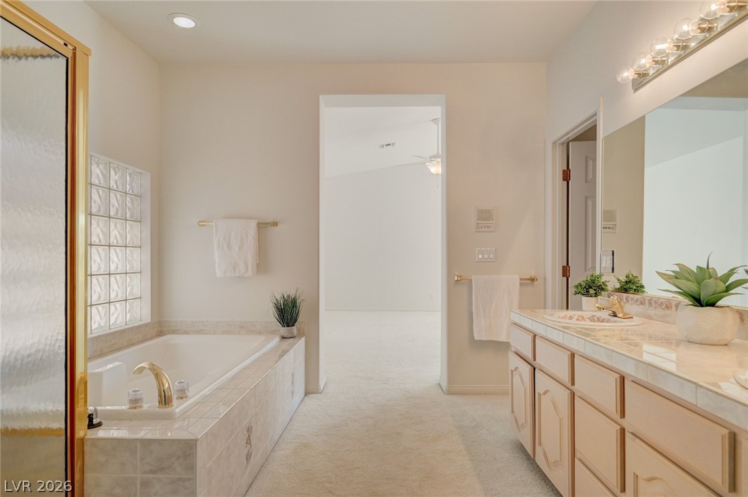 Bathroom with built-in tub, glass-block window, and long tiled vanity.