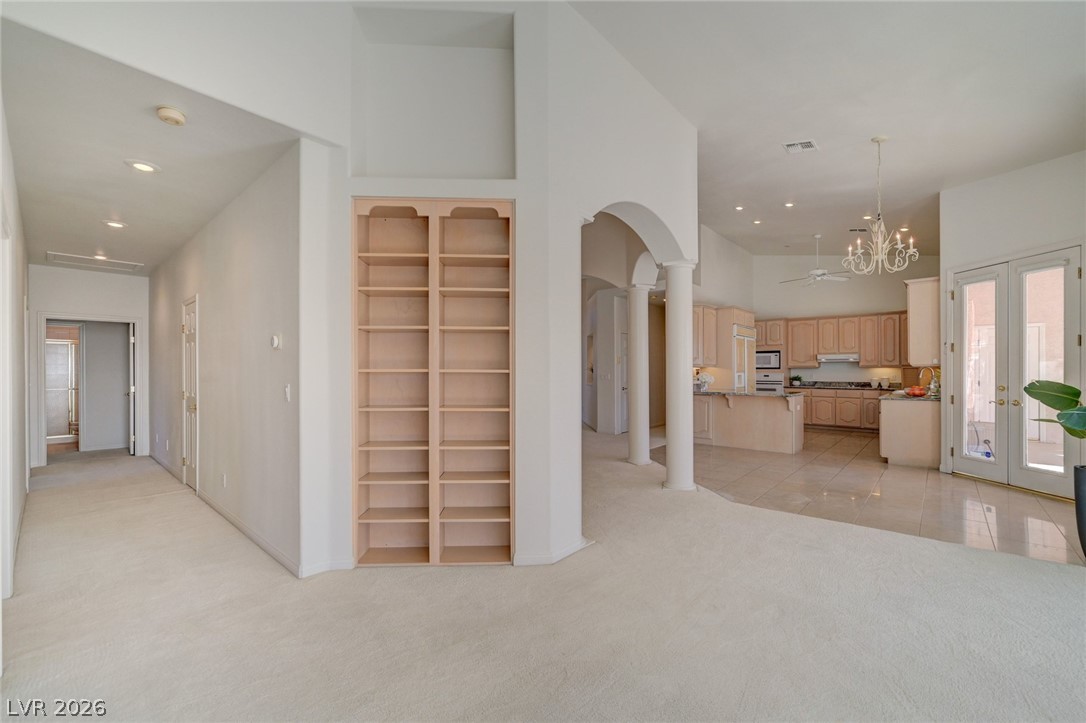 Open-plan interior with built-in shelves, arched columns, and a light-wood kitchen.