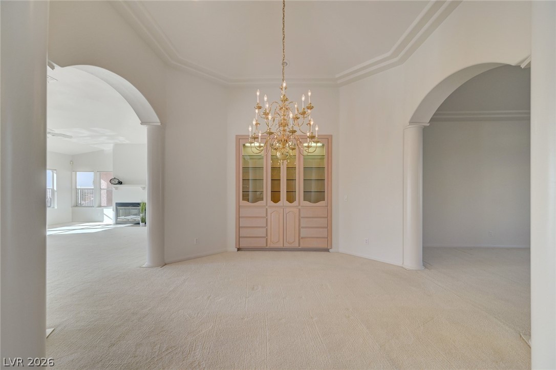 Empty formal dining room with a chandelier, built-in china cabinet, and wide arched openings.