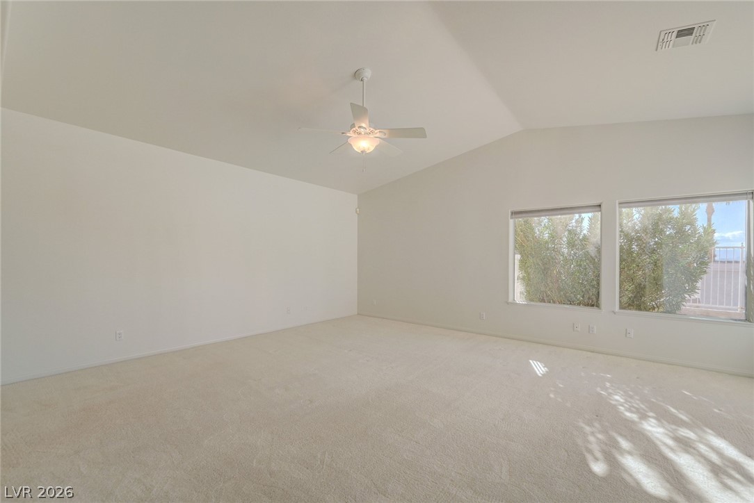 Empty carpeted room with a ceiling fan and two windows.
