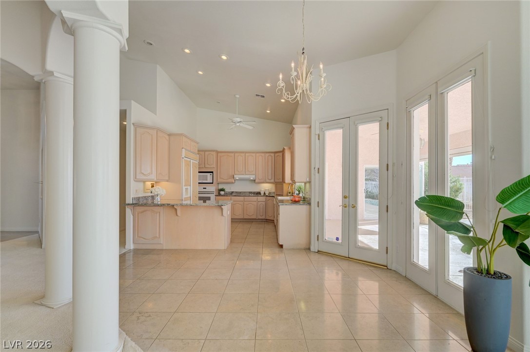 Kitchen with light wood cabinets, granite counters, tiled floors, and glass doors to a patio.
