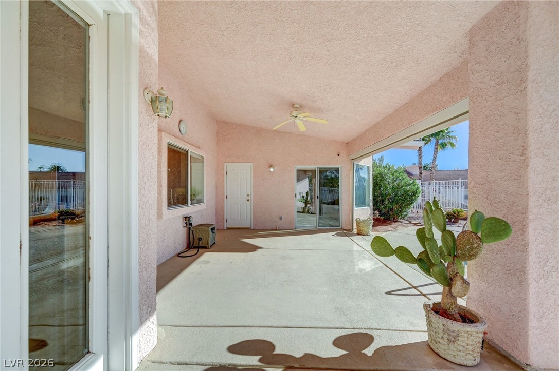 Covered patio with a ceiling fan and potted cactus beside sliding glass doors.