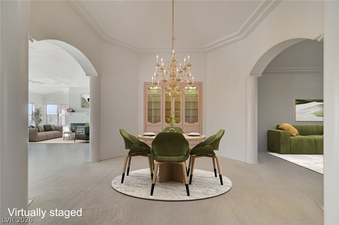 Dining room with a round table, green chairs, chandelier, and arched openings to adjoining living areas.