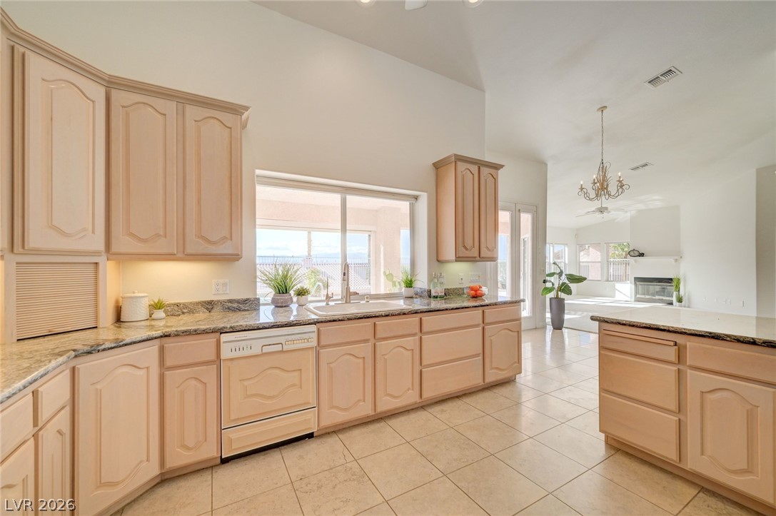 Bright kitchen with light wood cabinets, granite countertops, and an island opening to the living room.
