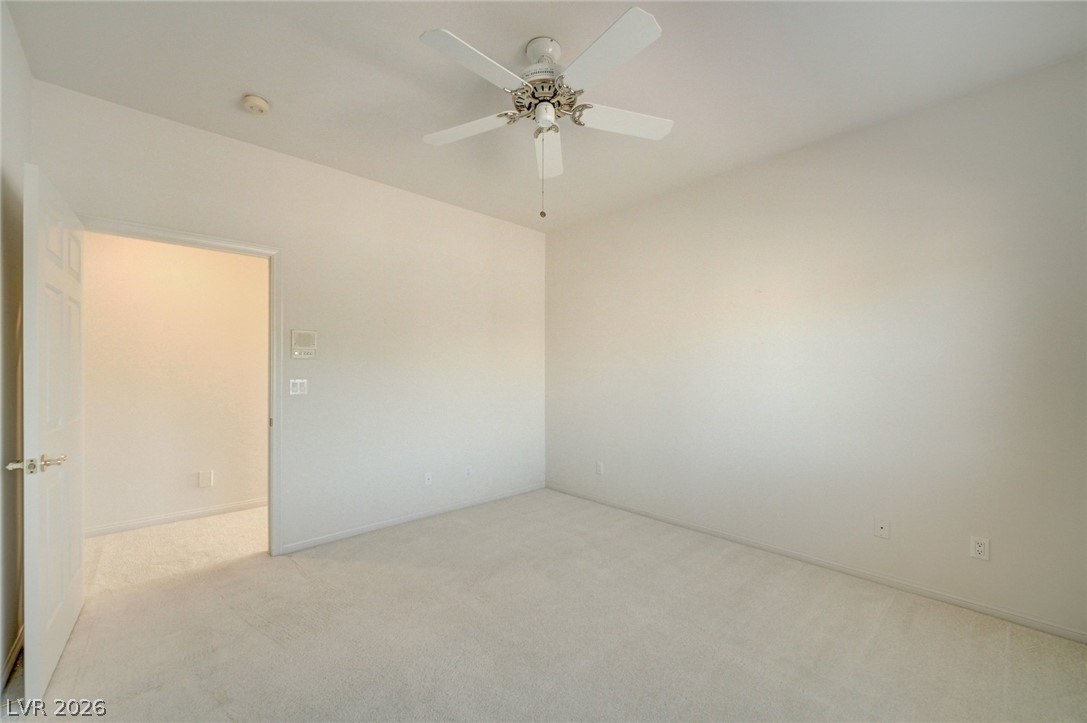 Empty carpeted bedroom with a ceiling fan and an open doorway.