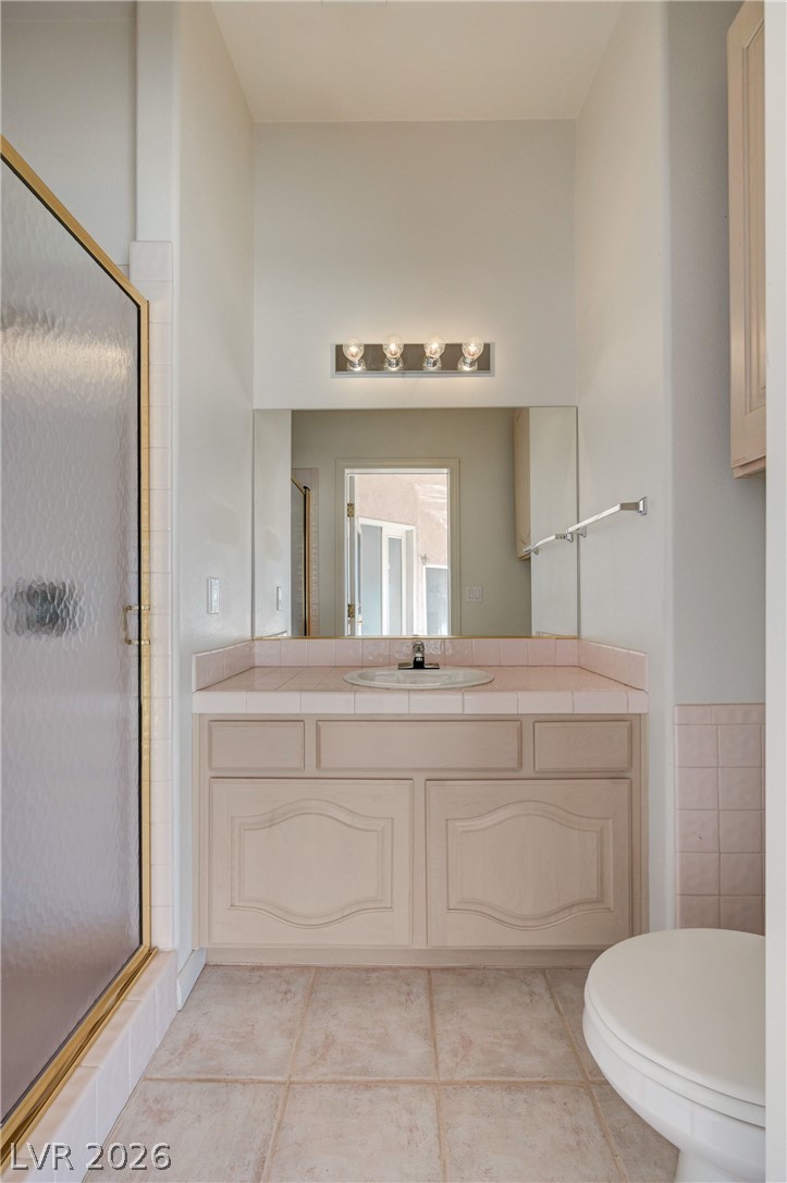 Bathroom vanity with pink tile, large mirror, and glass-enclosed shower.