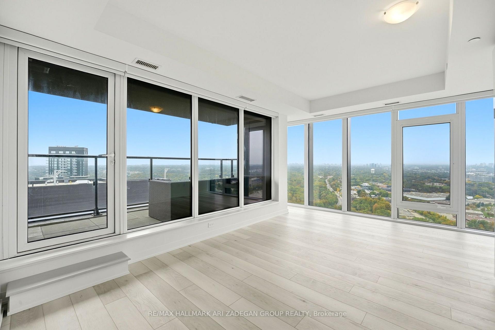 Vacant high-rise living area with floor-to-ceiling windows overlooking a balcony and city view.
