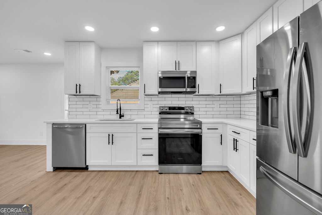 Renovated kitchen with white cabinets, subway tile backsplash, and stainless steel appliances.