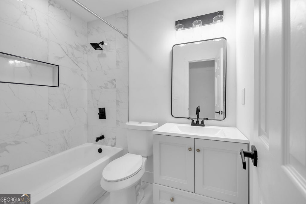 Bathroom with marble-look shower tile, a white tub, and a vanity with dark fixtures.