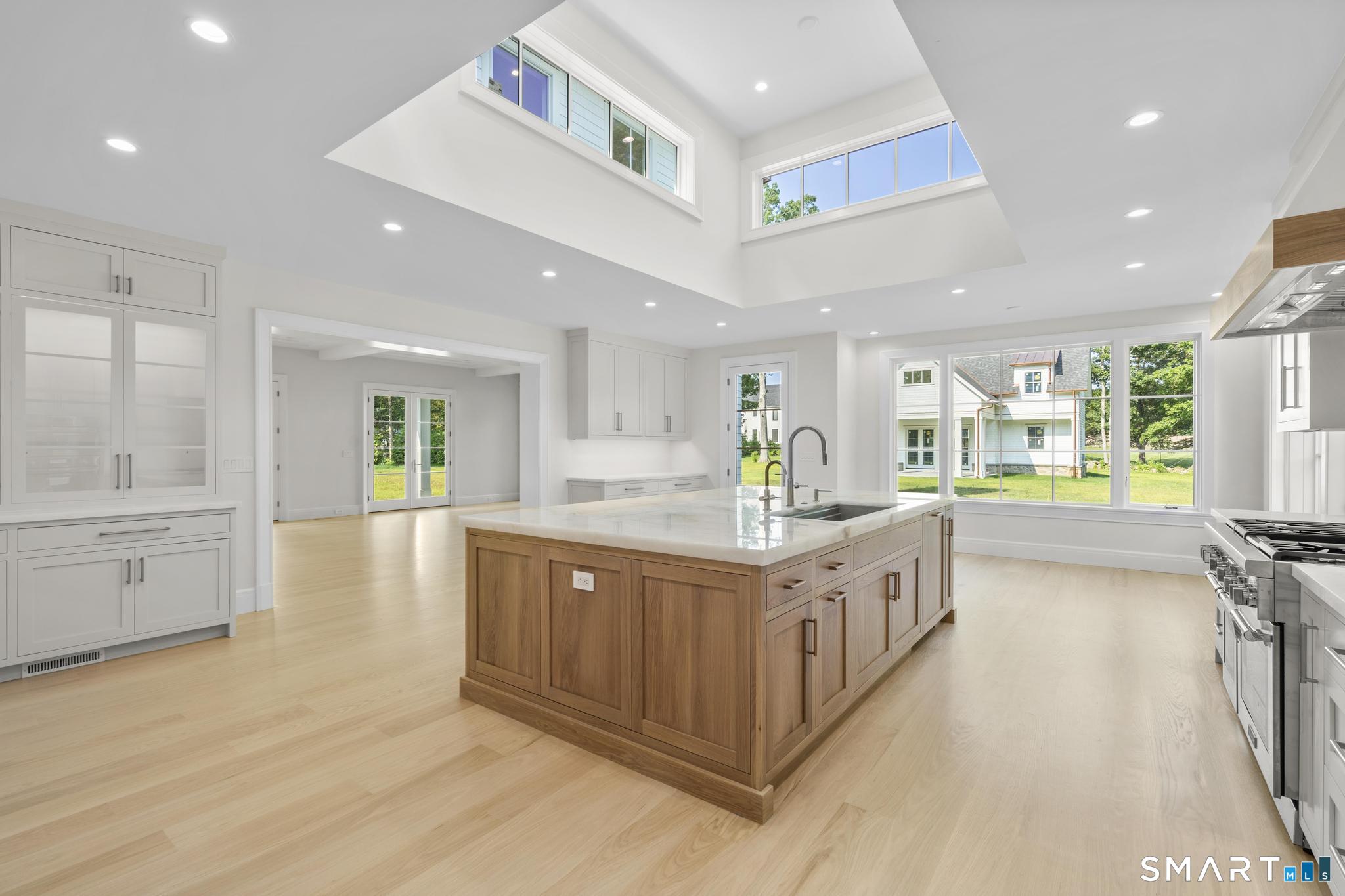 Modern kitchen with a wood-paneled island, white cabinets, and high clerestory windows.