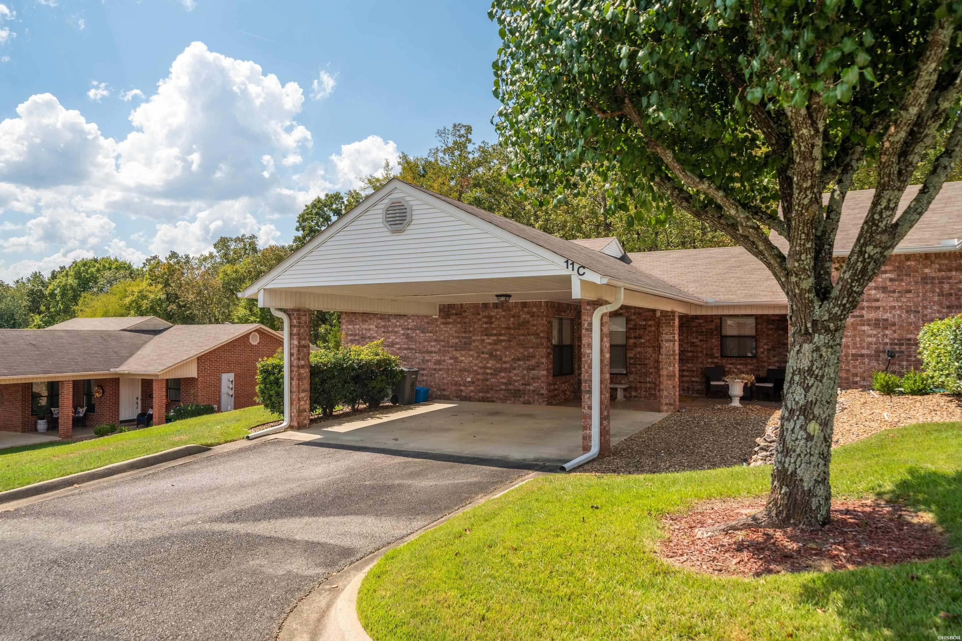 Brick home with a covered carport marked 11C and a large shade tree beside the driveway.