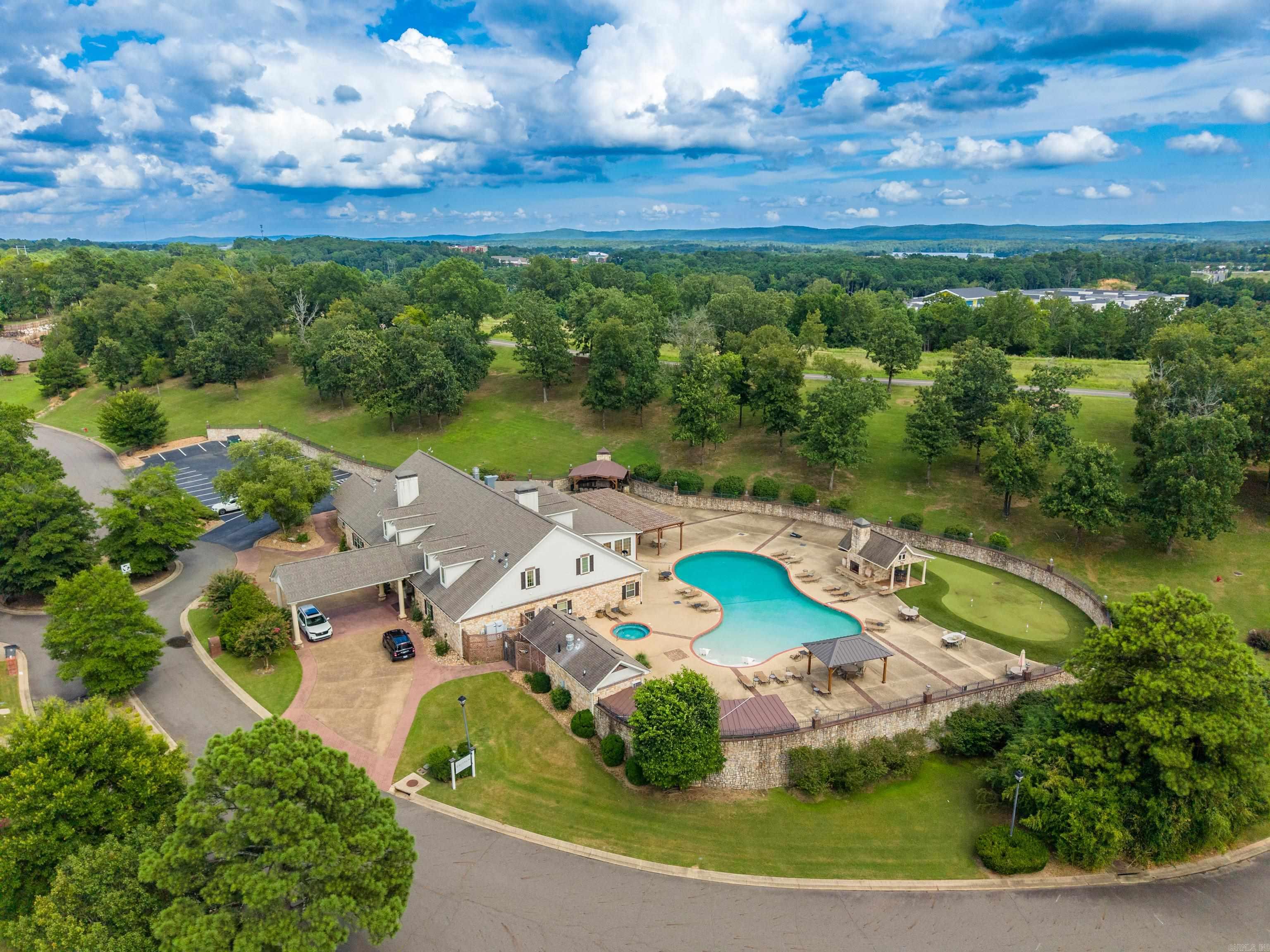 Aerial view of a clubhouse and freeform pool, surrounded by trees and landscaped grounds.
