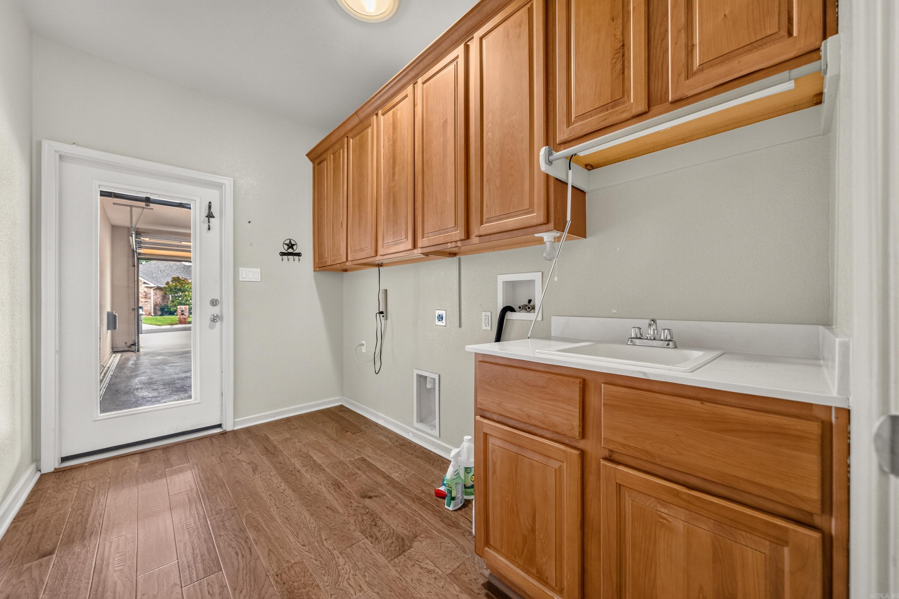 Laundry room with wood cabinets, a white utility sink, and a glass-panel exterior door.