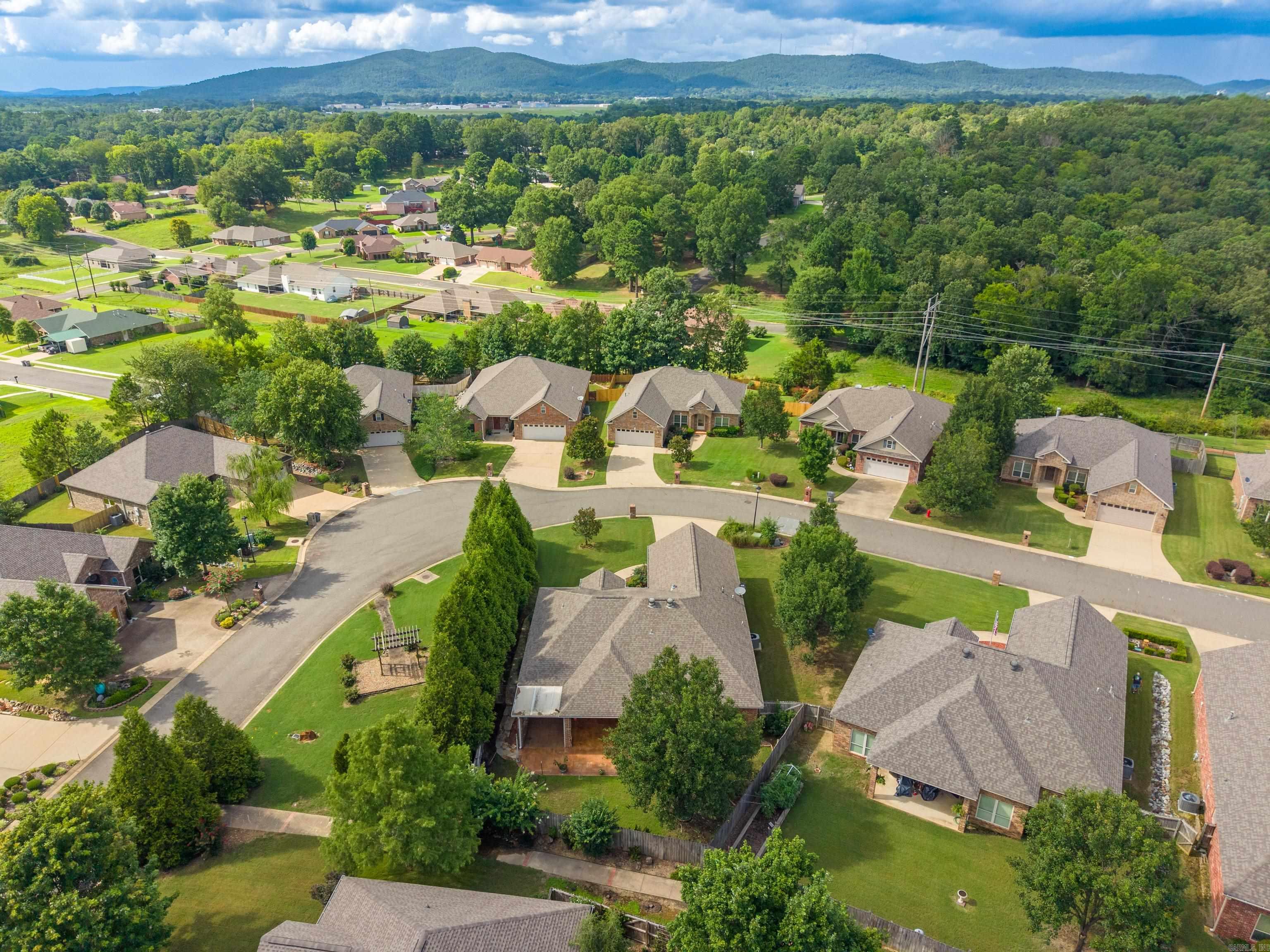 Aerial view of a residential cul-de-sac with wooded hills and mountains beyond.