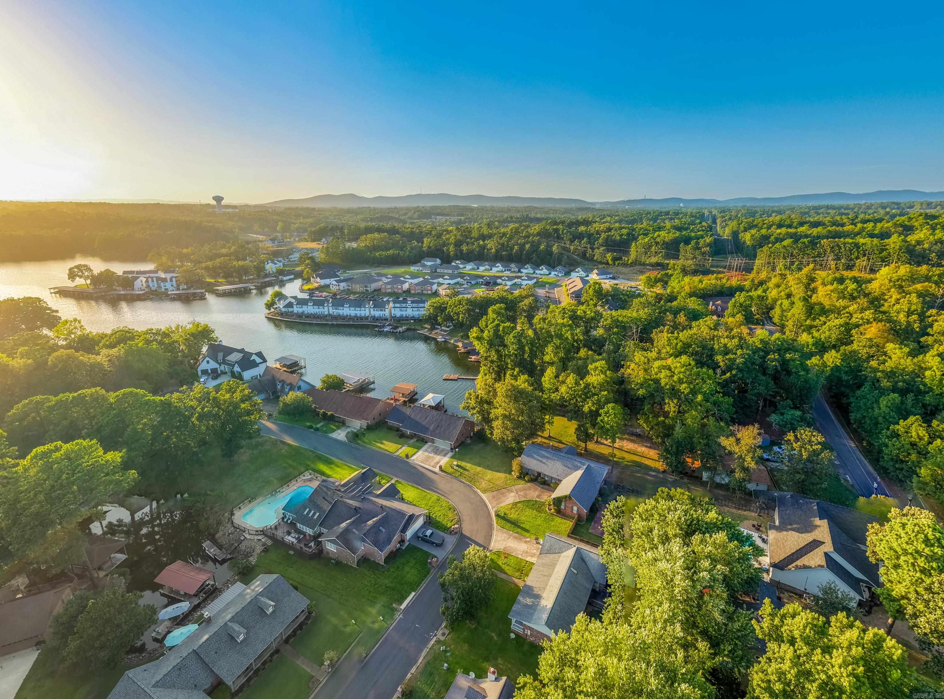 Aerial view of a wooded cove neighborhood with waterfront homes, docks, and a swimming pool.