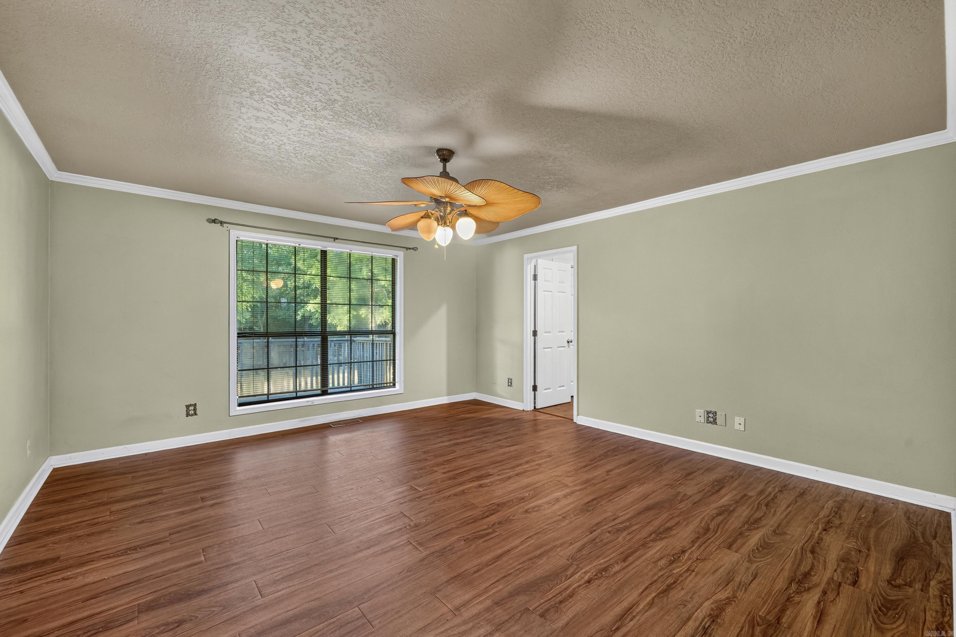 Empty room with wood-look flooring, a large window, and a ceiling fan with light.