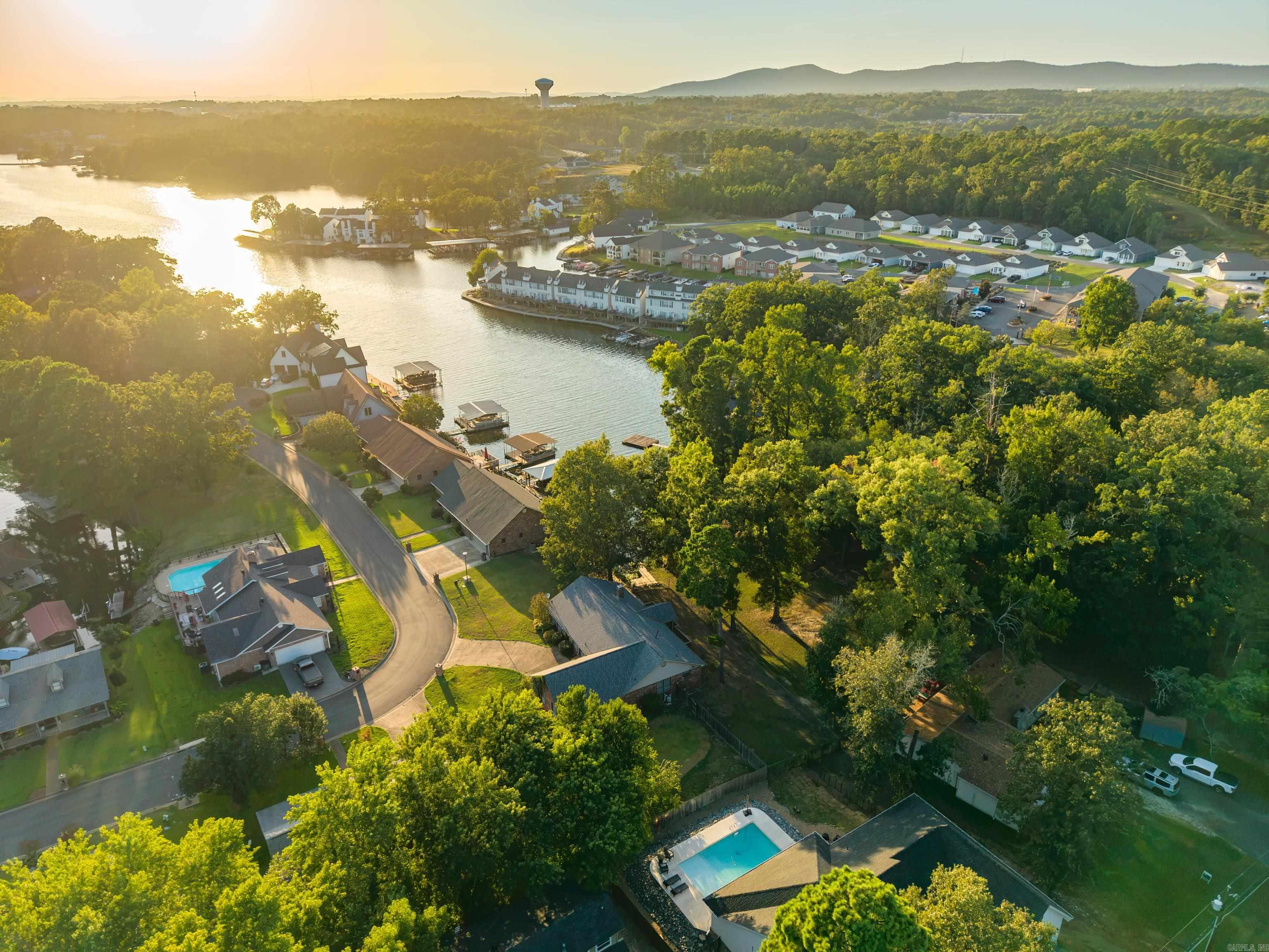 Aerial view of a lakeside neighborhood with docks, wooded homes, and swimming pools.