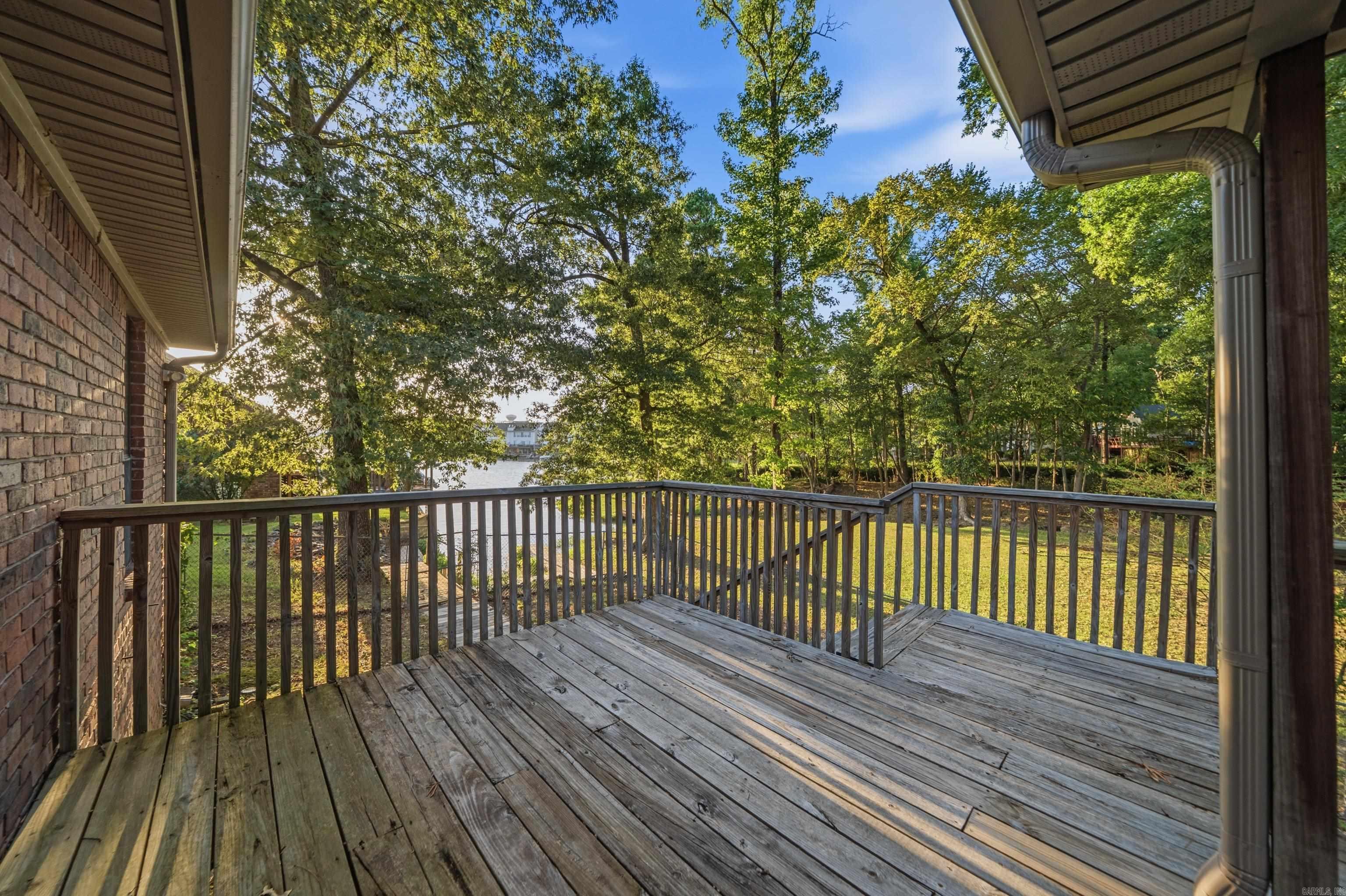 Wooden deck overlooking a wooded shoreline and water.