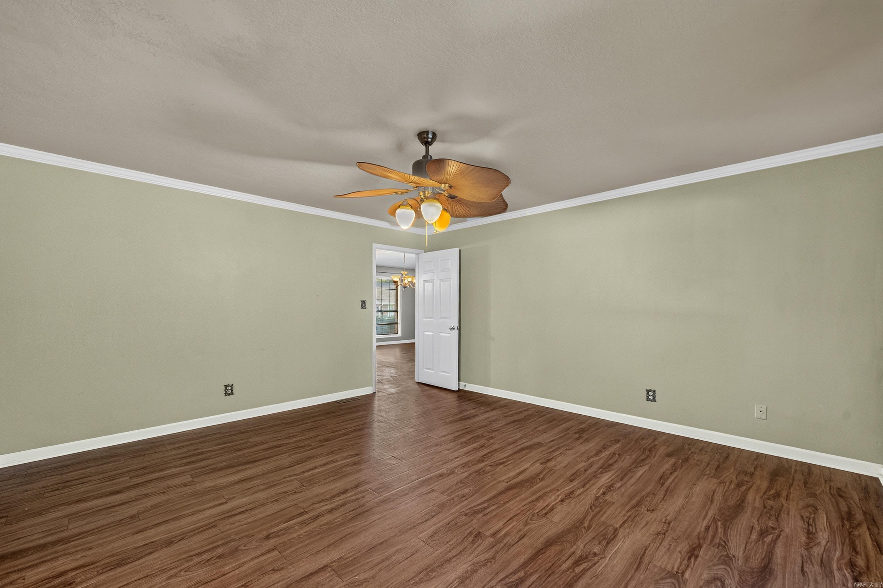 Unfurnished room with wood-look flooring, pale green walls, and a wooden-blade ceiling fan.