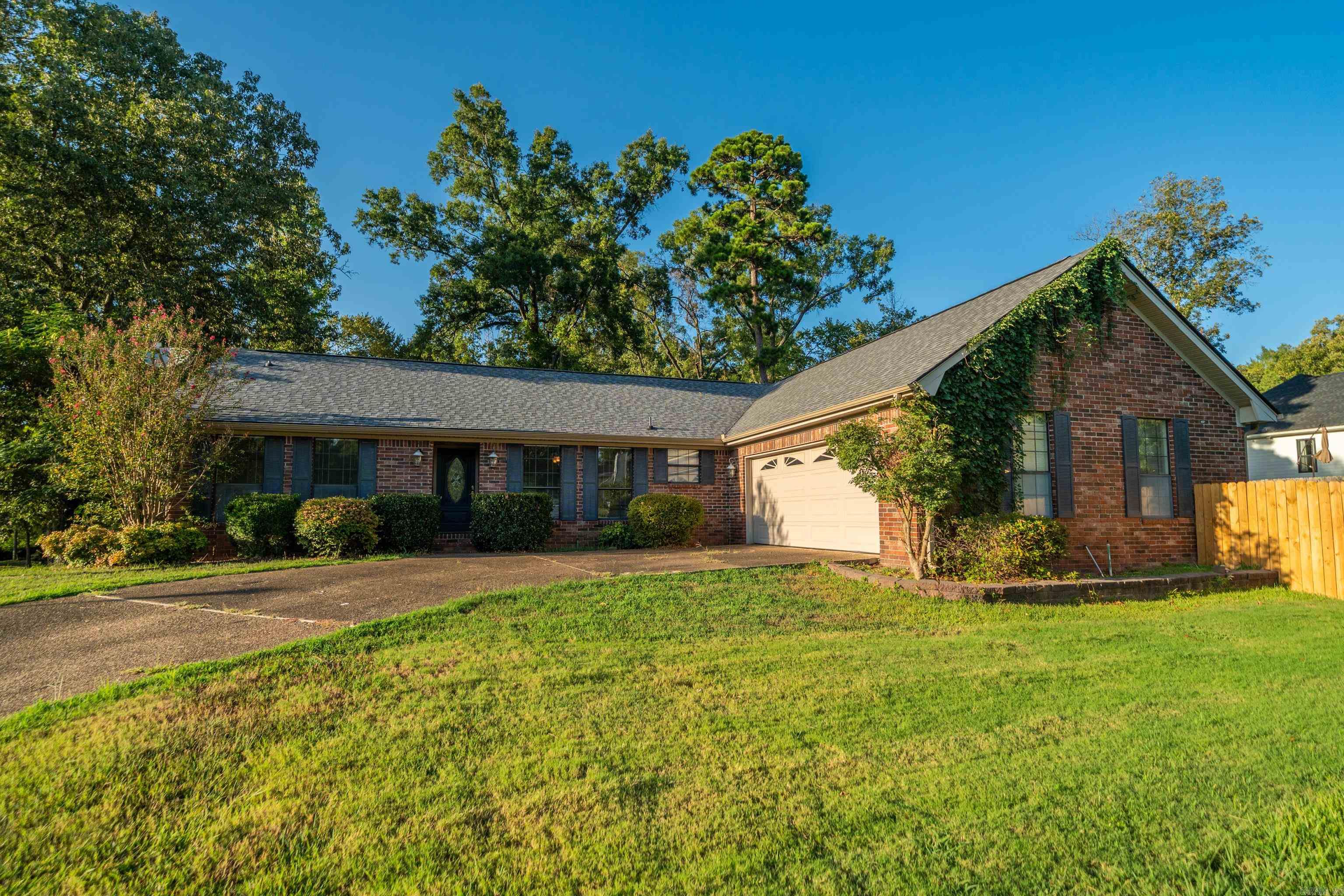 Brick house with a two-car garage, ivy-covered gable, wide driveway, and front lawn.