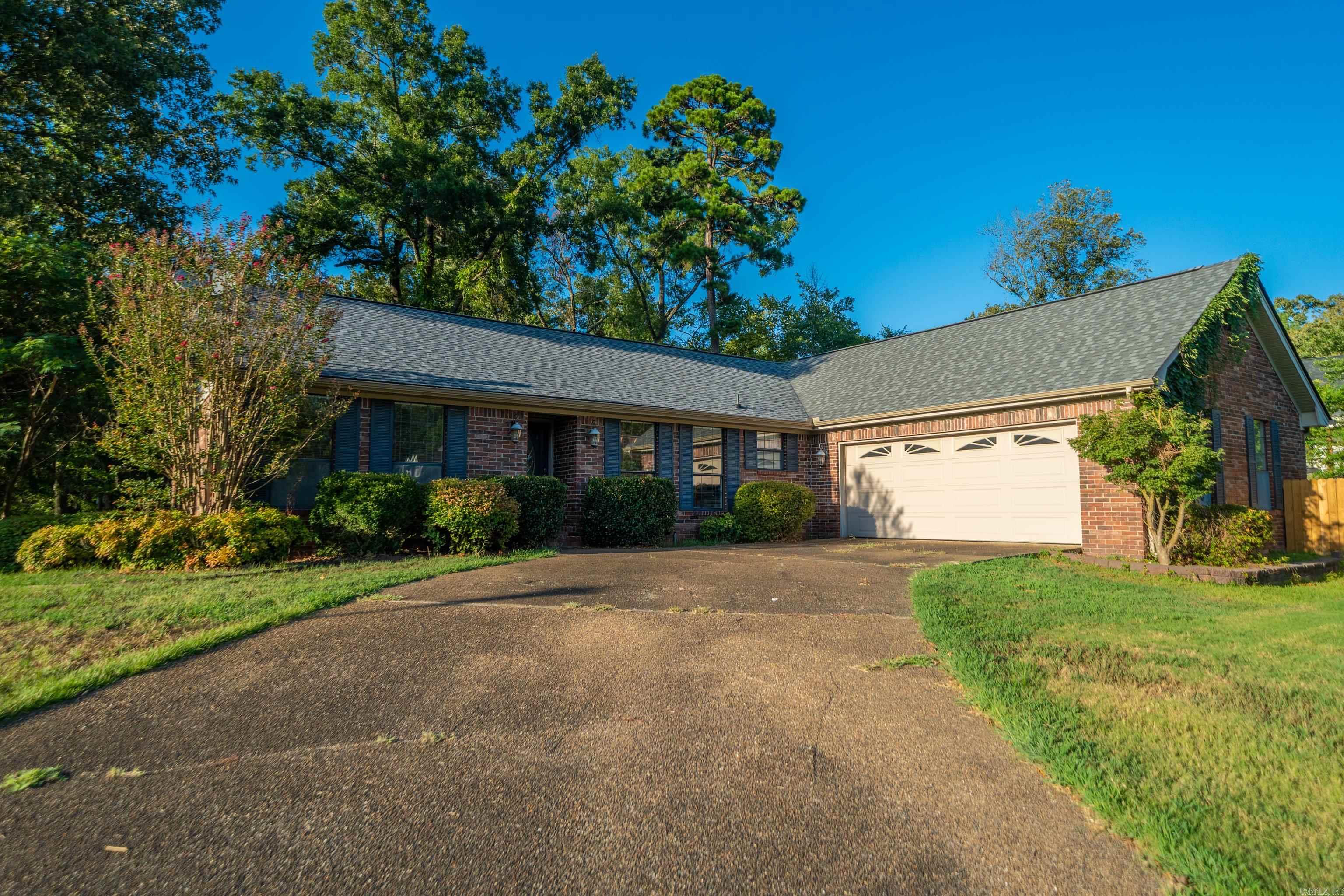 Single-story brick house with blue shutters, an attached two-car garage, and a wide driveway.