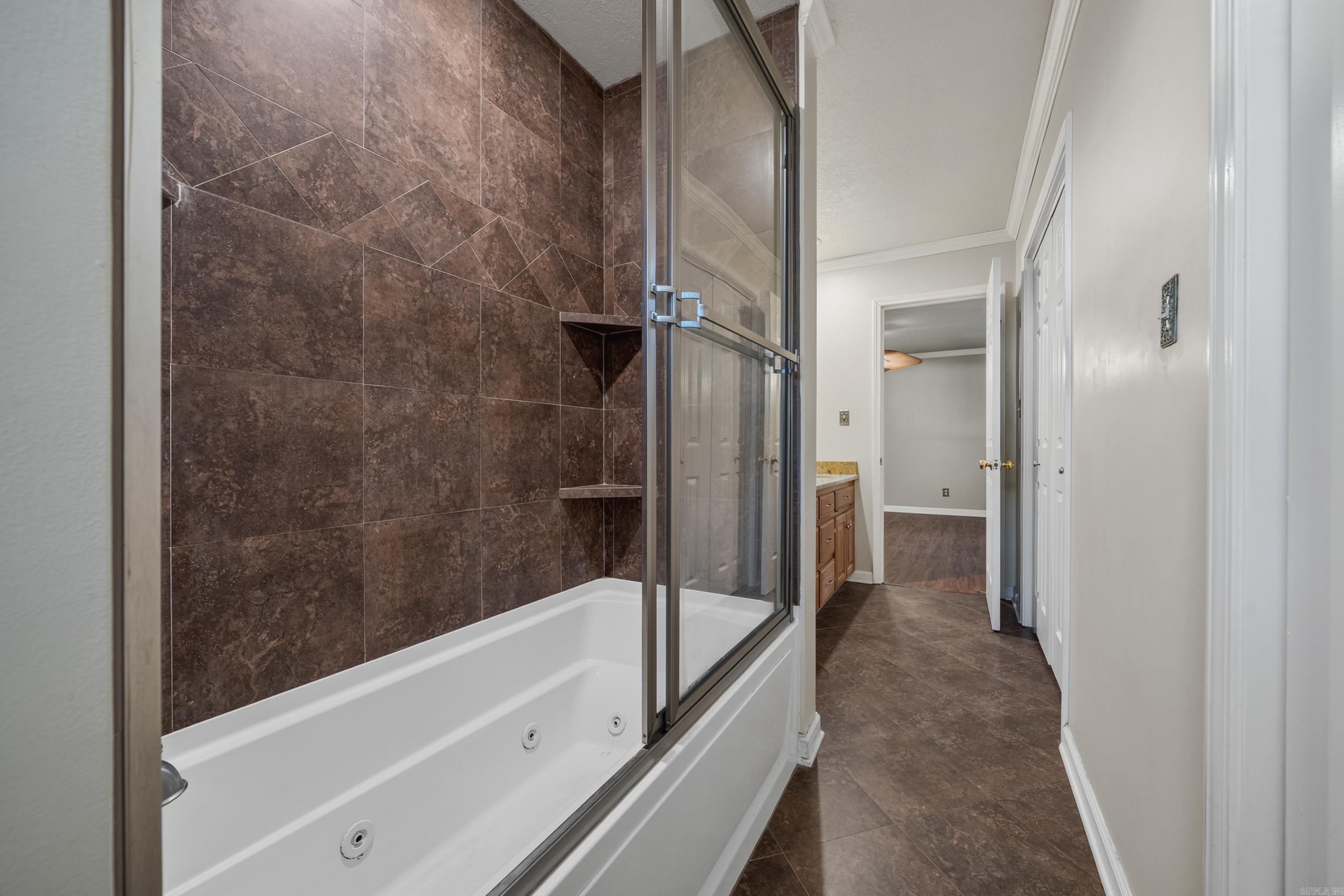 Bathroom with a jetted tub, glass shower enclosure, and brown tile walls.
