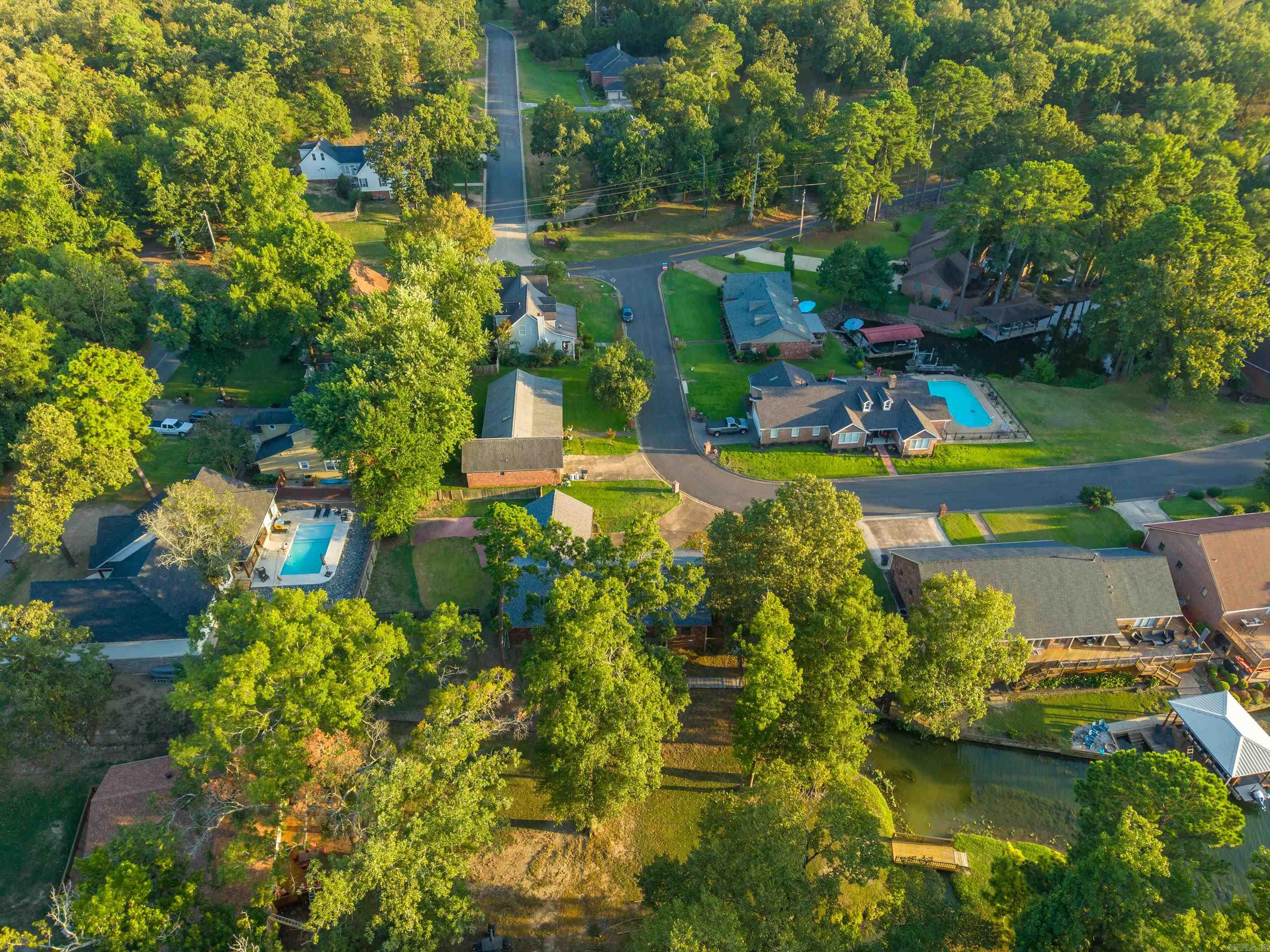 Aerial view of a wooded neighborhood with homes, swimming pools, and waterfront docks.