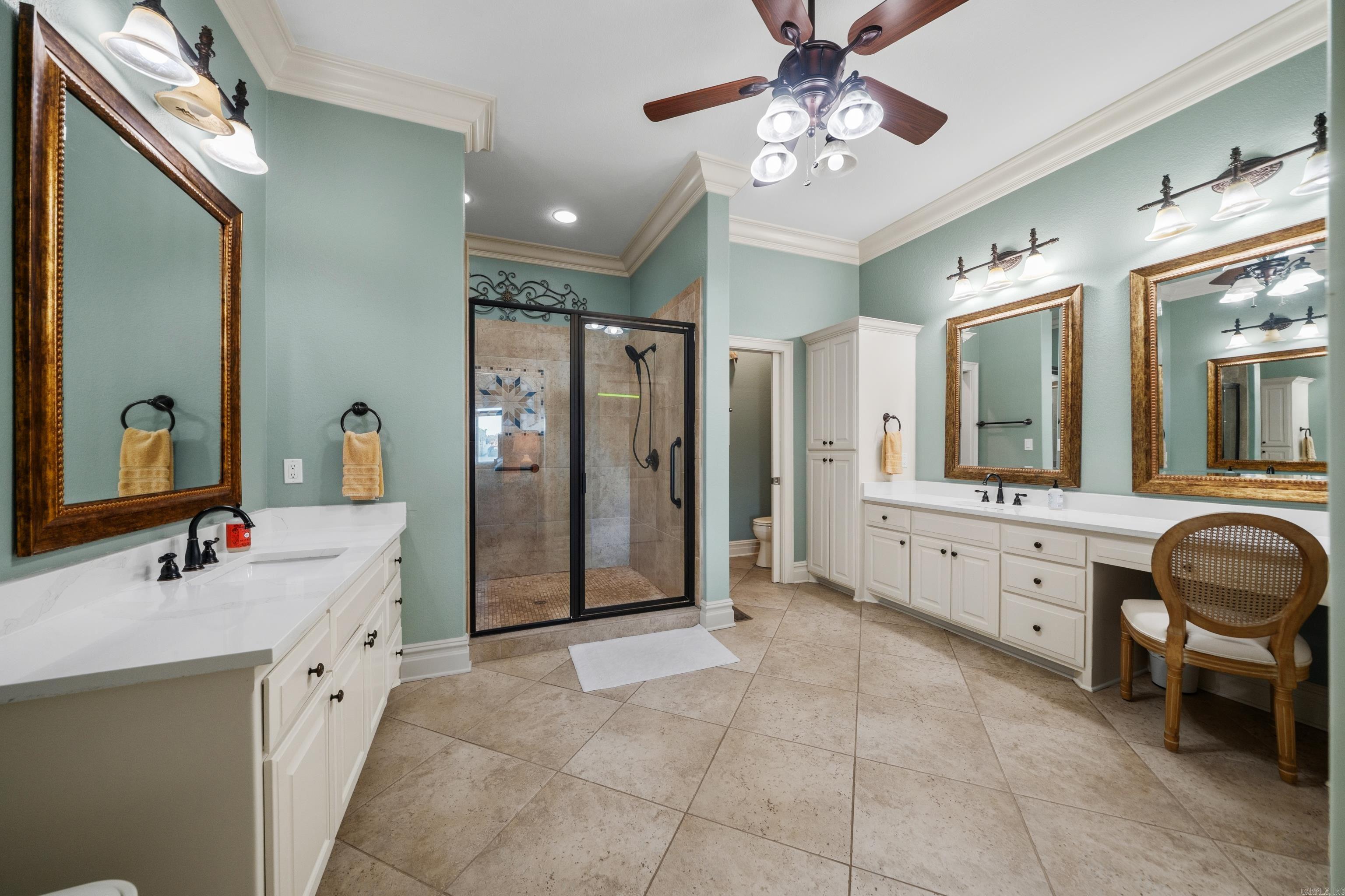 Spacious bathroom with double white vanities, aqua walls, and a glass-enclosed tiled shower.