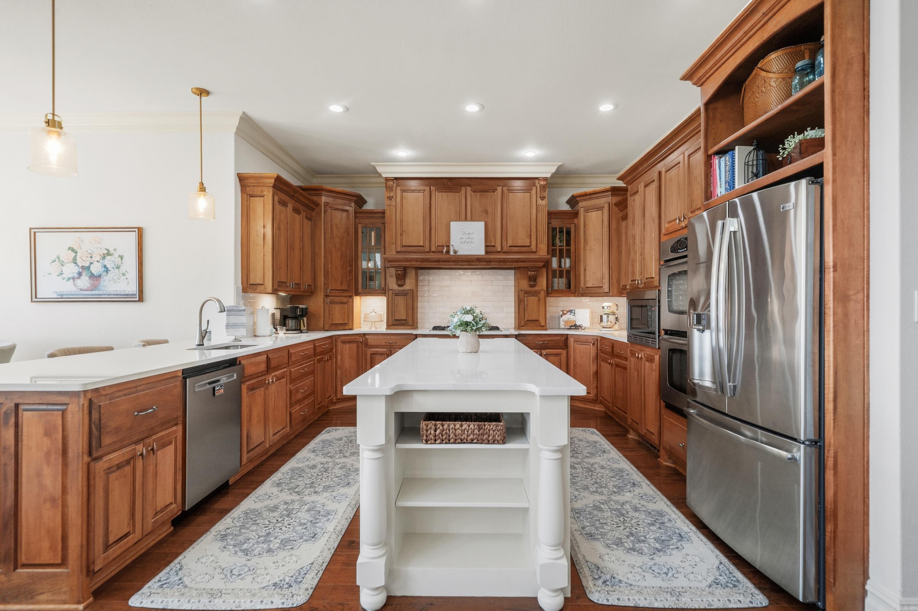 Kitchen with extensive wood cabinetry, stainless steel appliances, and a large white island.