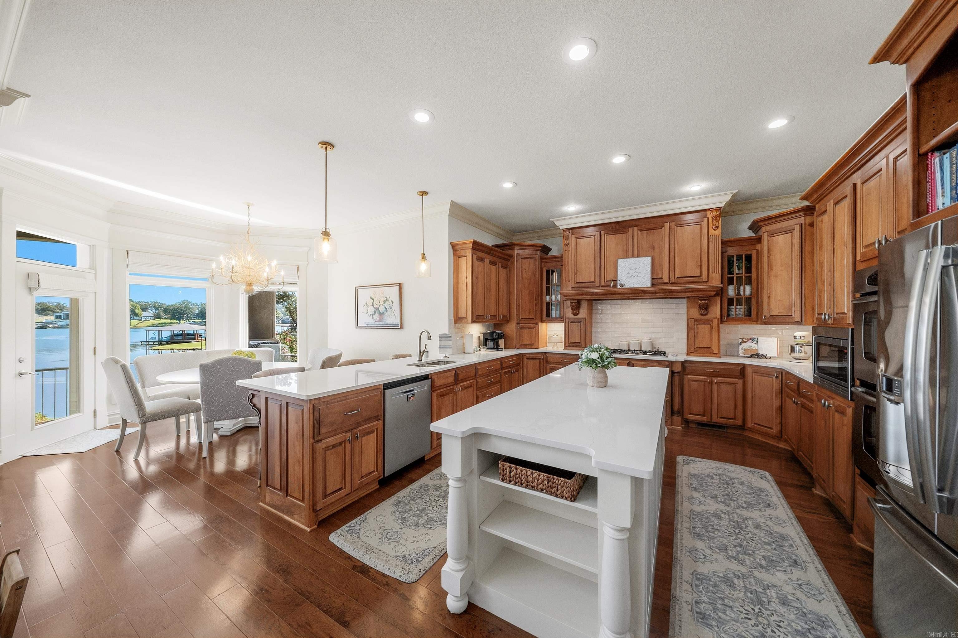 Furnished kitchen with wood cabinetry, a large white island, and water views through the dining-area windows.