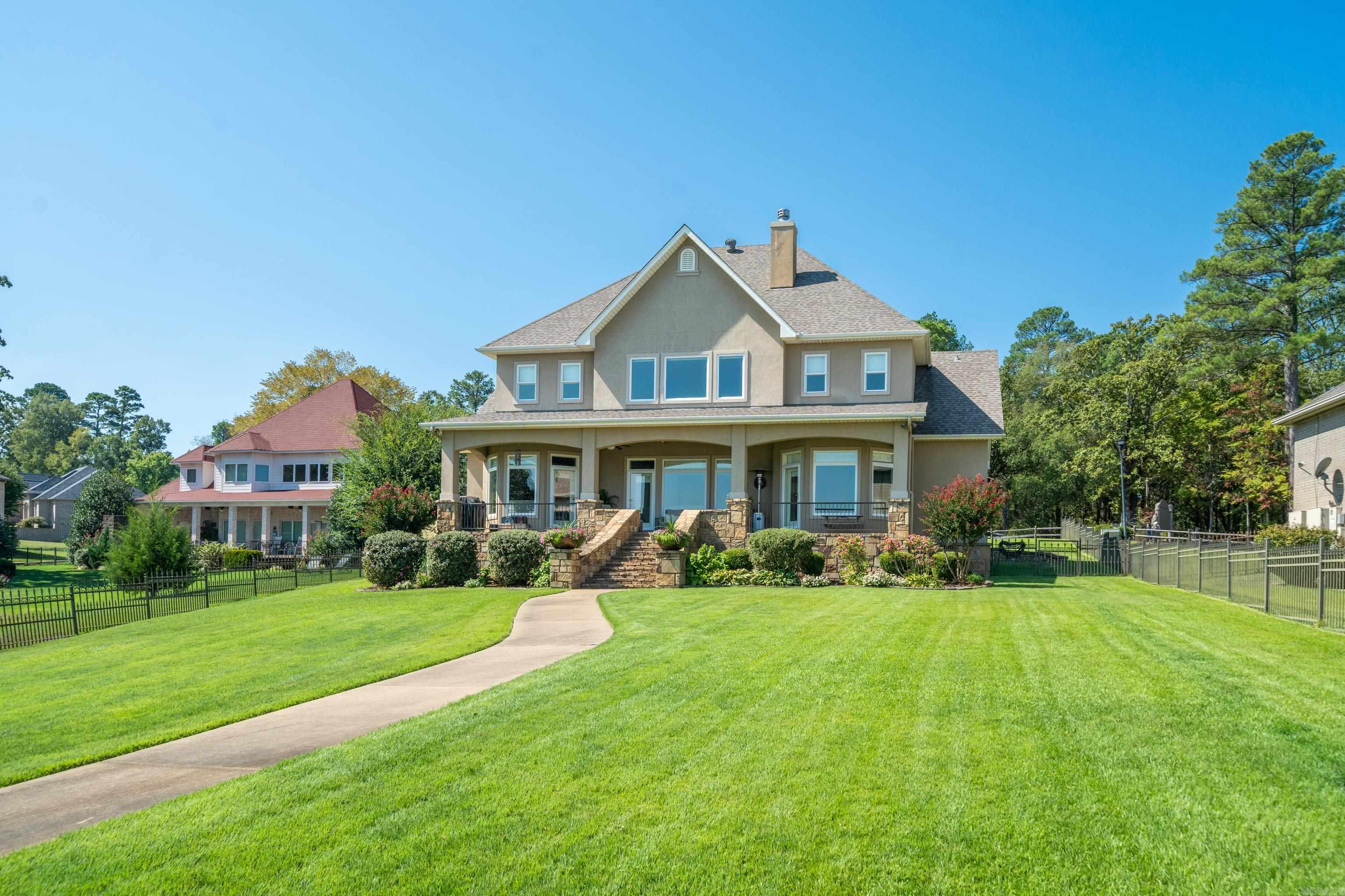 Two-story home with a covered porch, stone steps, and a curved walkway across the lawn.