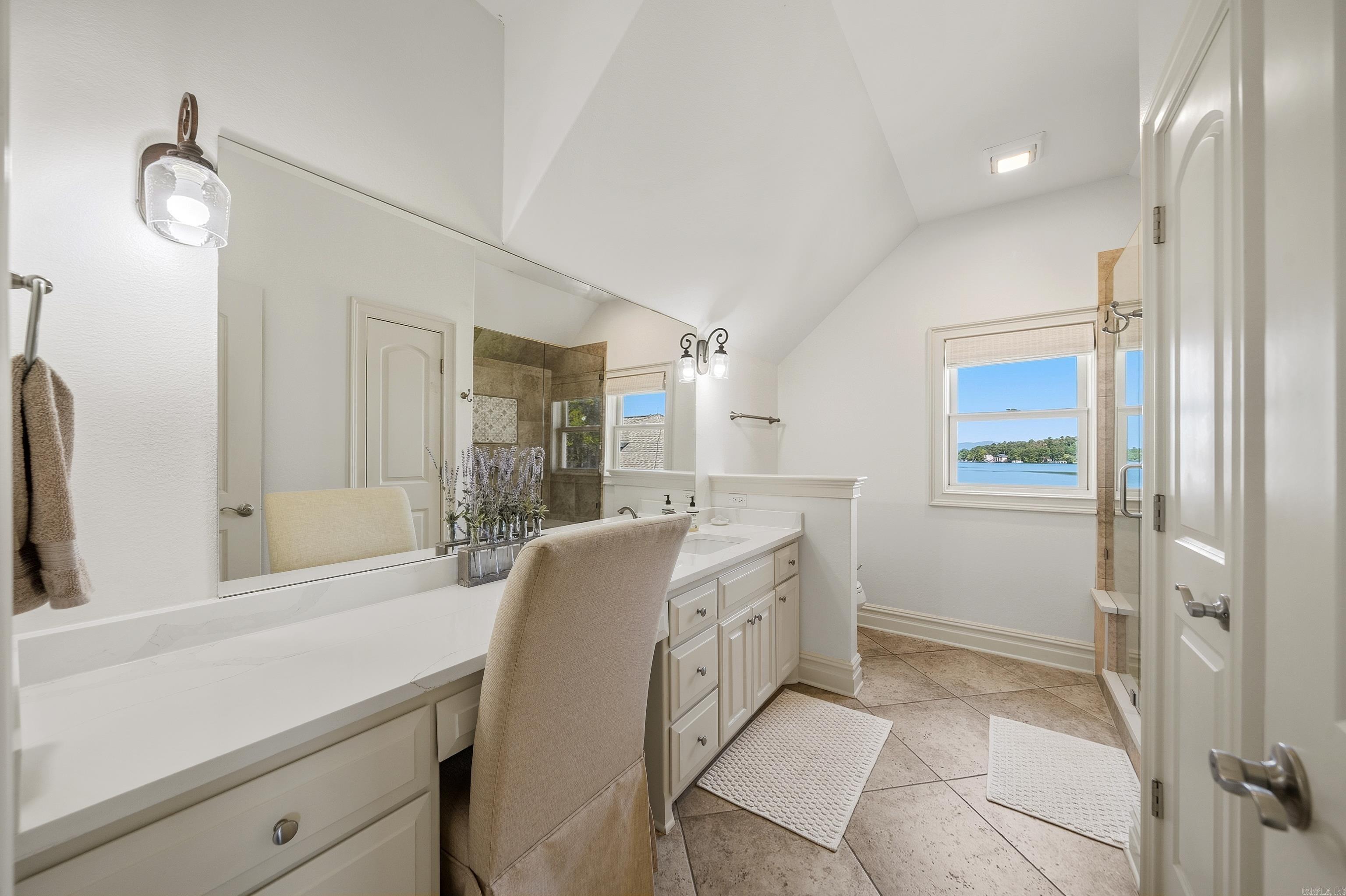 Bright bathroom with a long white vanity and a lake view through the window.