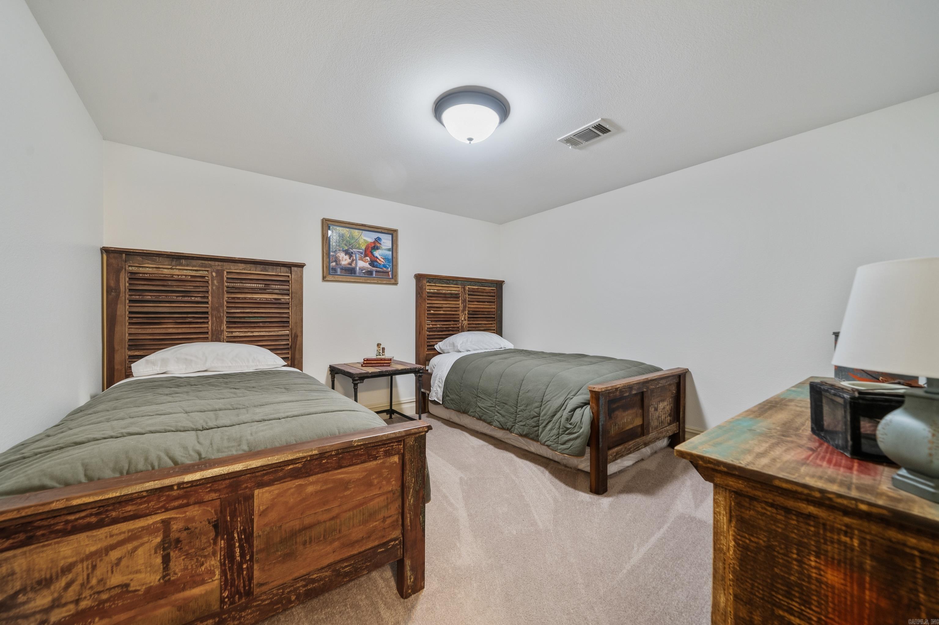 Bedroom with two single beds, rustic wooden frames, green bedding, and a table between them.