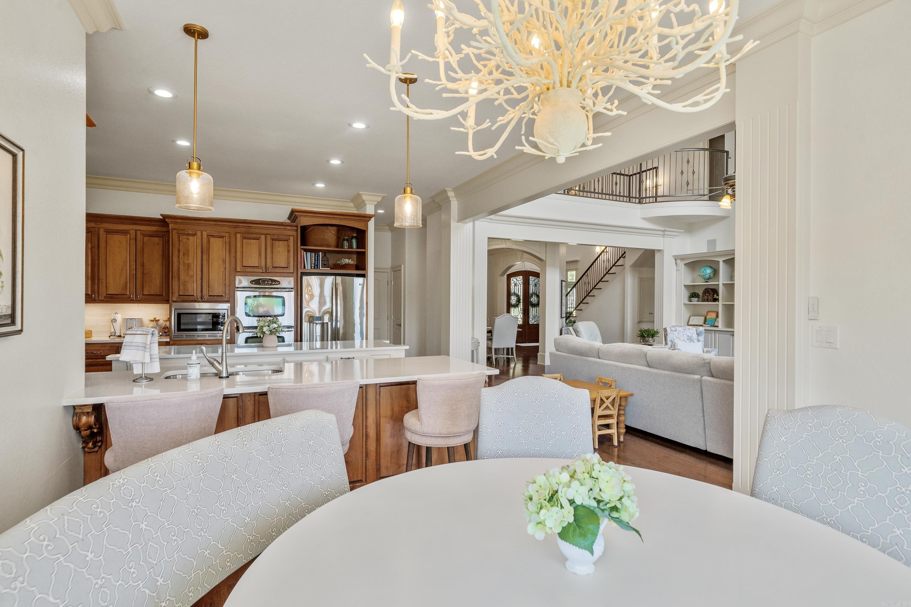 Open-plan kitchen and living room with a large island, wood cabinets, and branching chandelier.