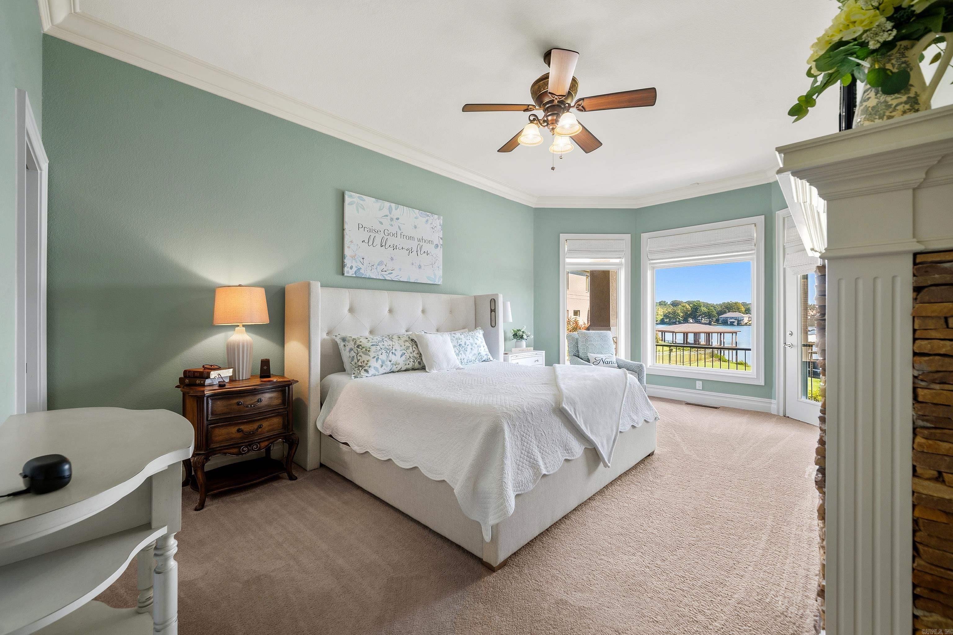 Bedroom with a white upholstered bed and lake views through the windows.