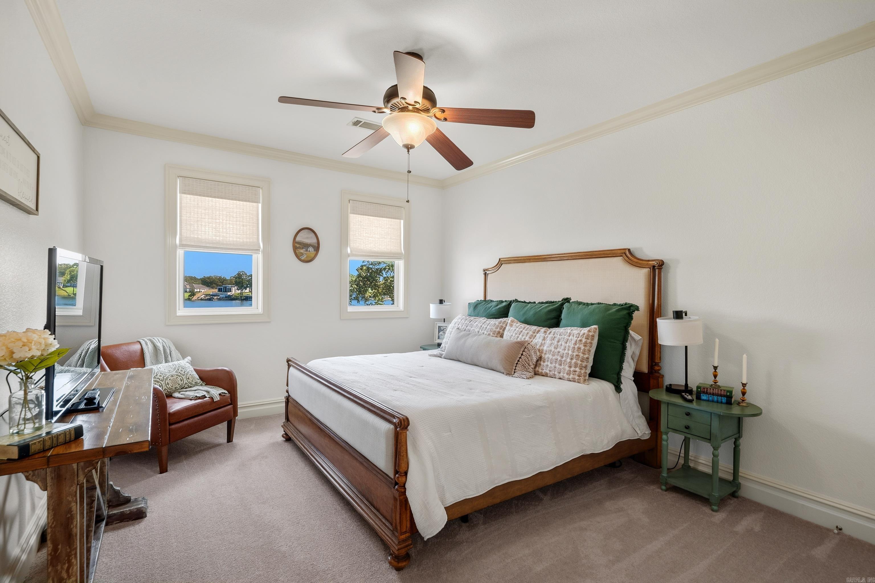 Furnished bedroom with a wooden bed and water views through two windows.