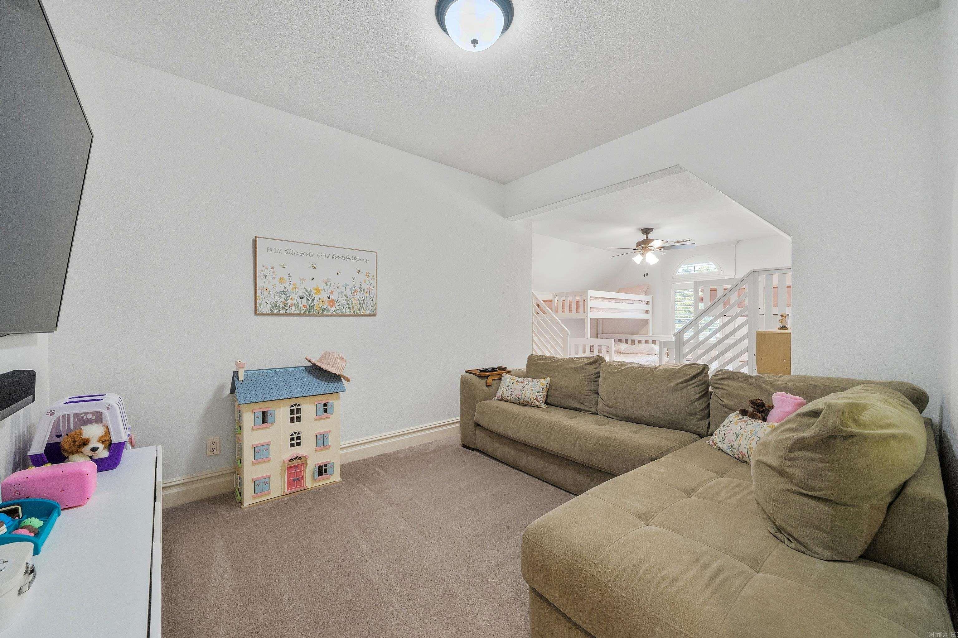 Living room with a beige sectional and an open children's bunk-bed area behind it.