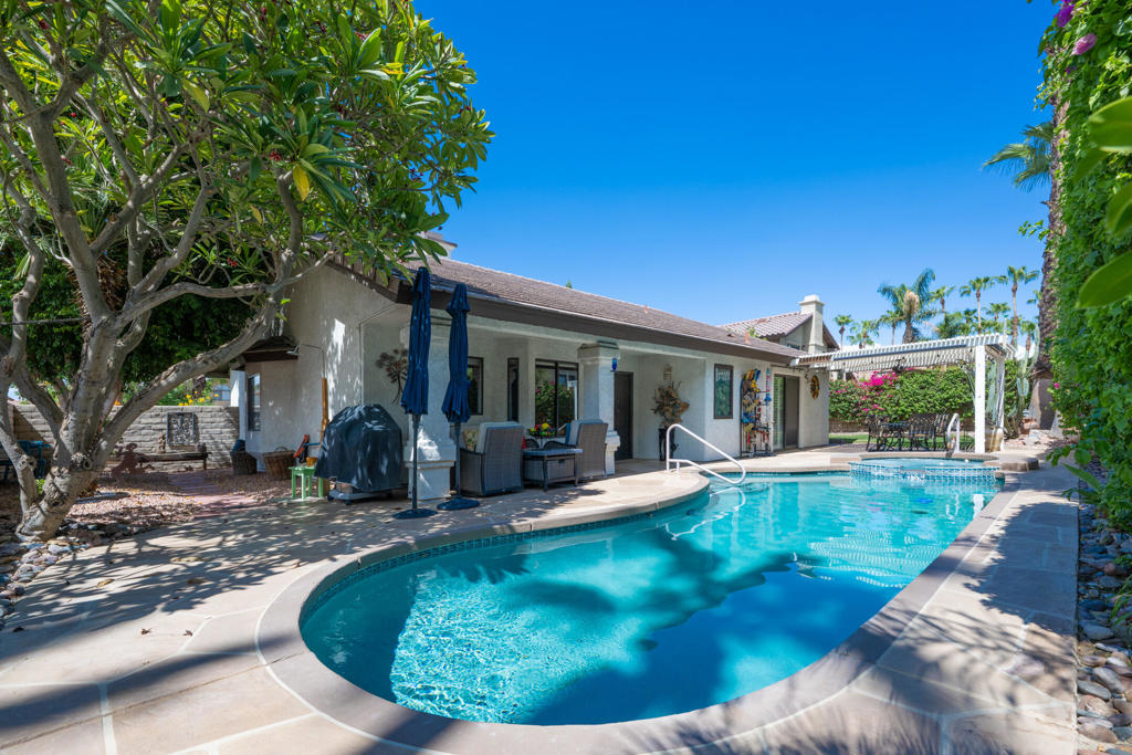 Curved backyard pool beside the home's covered patio and outdoor seating.