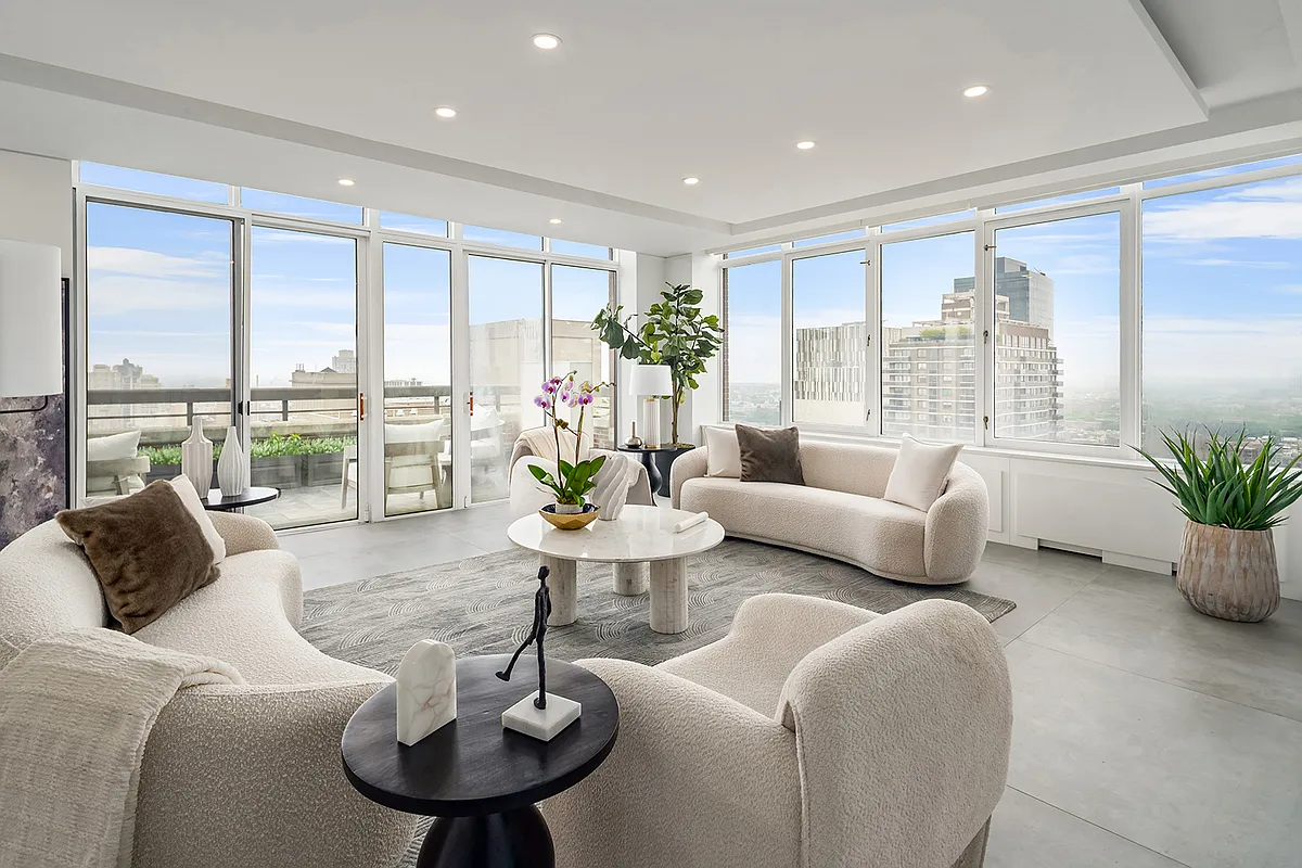 Bright staged living room with floor-to-ceiling windows, curved seating, and city views.