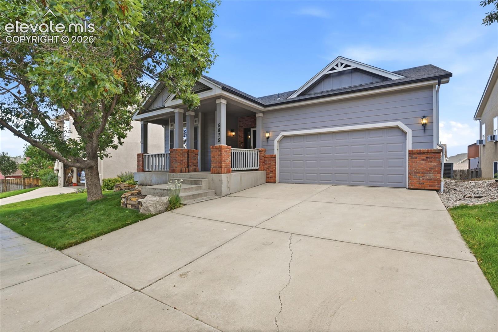 Gray-sided home with brick accents, a covered porch, and a two-car garage.
