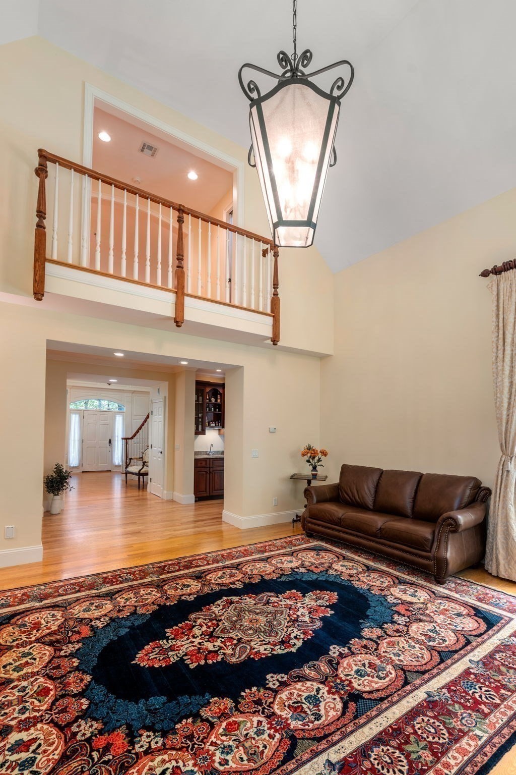 Living room with a vaulted ceiling, ornate blue rug, and brown leather sofa.
