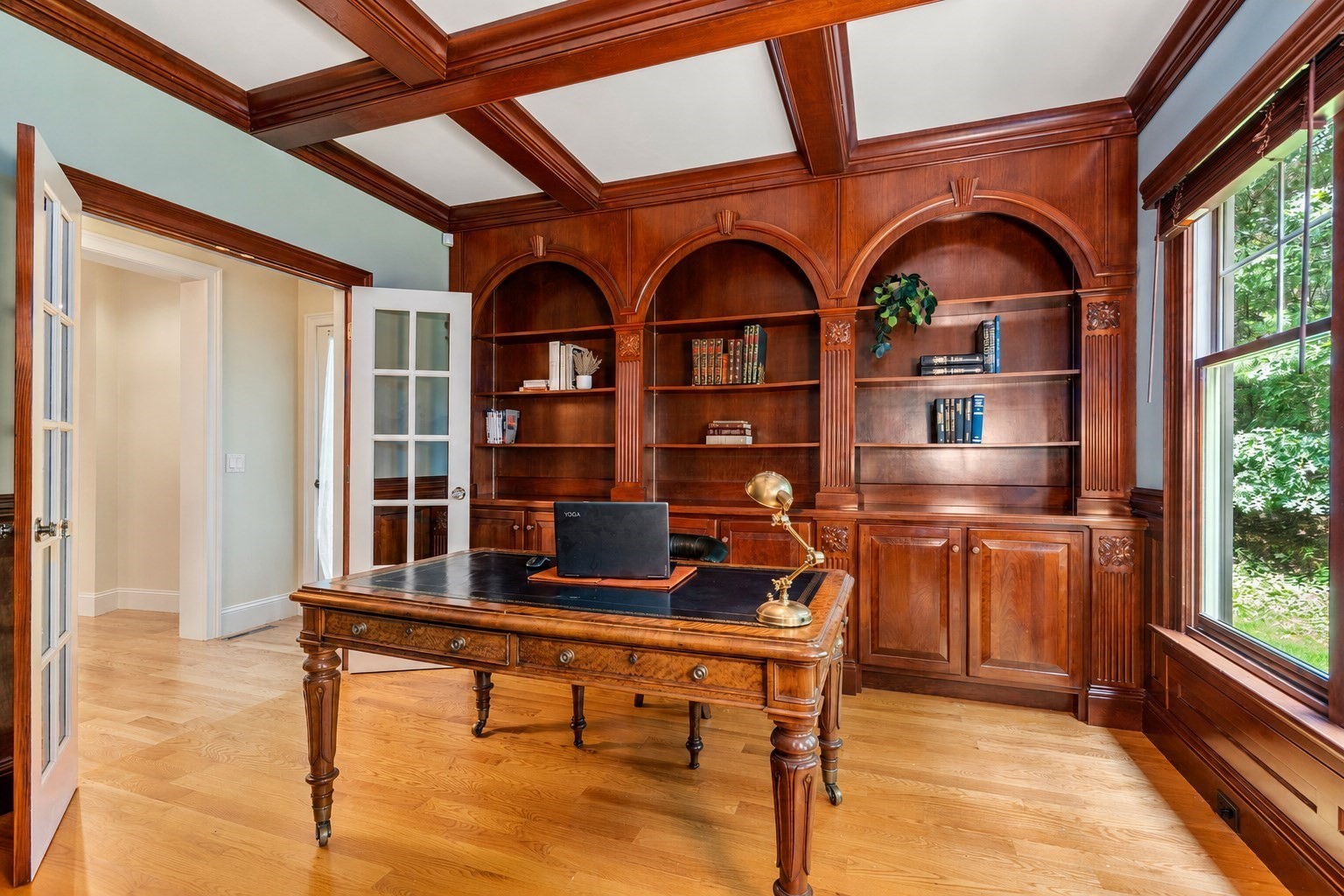 Home office with ornate cherrywood built-ins, a coffered ceiling, and a large desk.