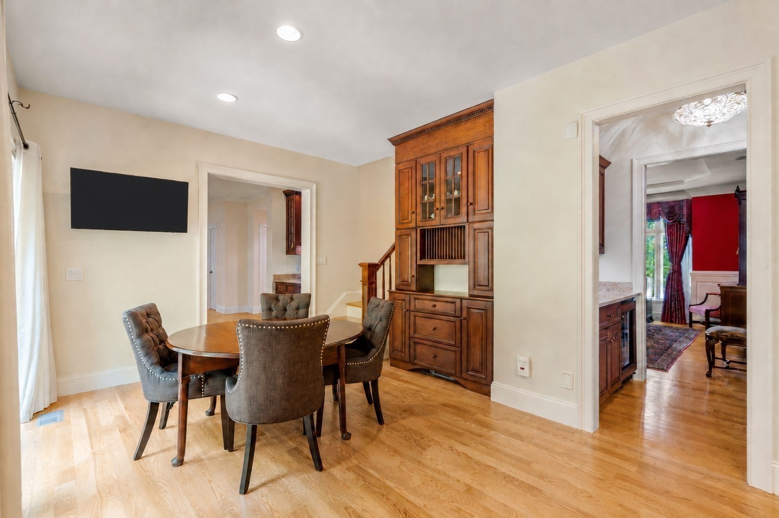 Dining room with a round table, upholstered chairs, and a large built-in wooden cabinet.