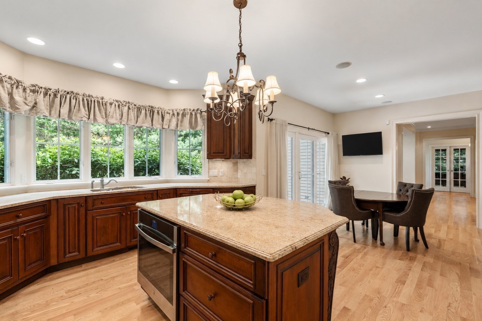 Kitchen with a granite island, dark wood cabinetry, and wide garden-facing windows.