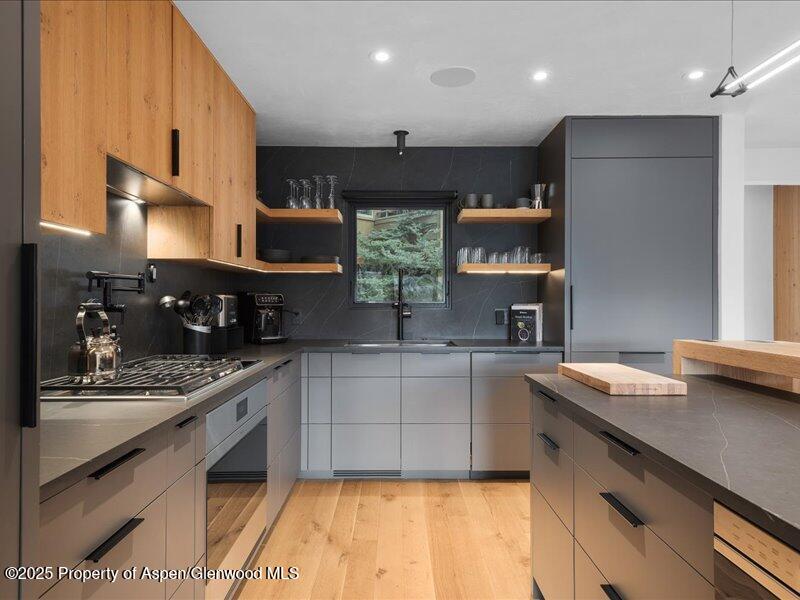 Modern kitchen with gray cabinetry, warm wood finishes, and a large island.