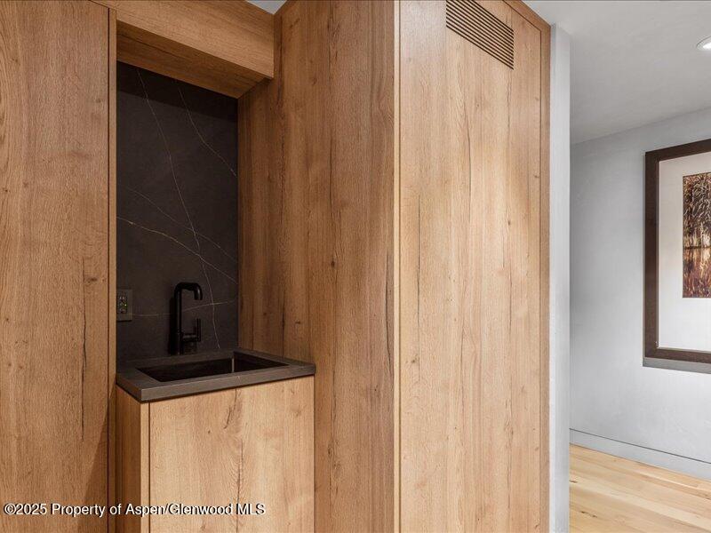 Built-in wet bar with a dark sink, black faucet, and warm wood cabinetry.