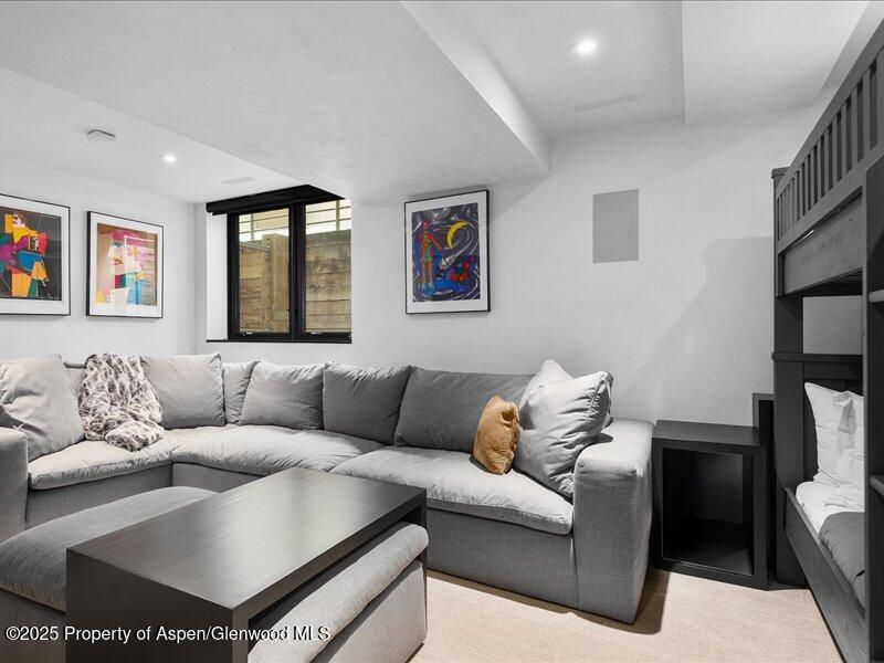 Living room with a gray sectional, colorful framed art, and a built-in bunk bed.